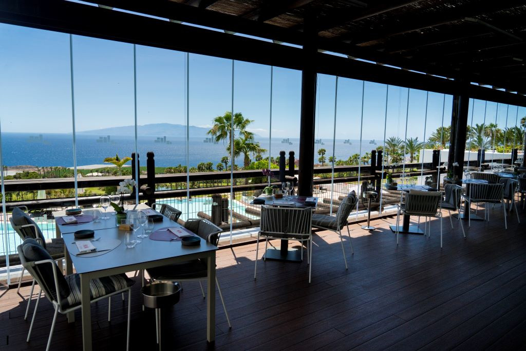 Restaurant met uitzicht op zee en La Gomera vanaf Tenerife, tafels klaargemaakt om te eten.