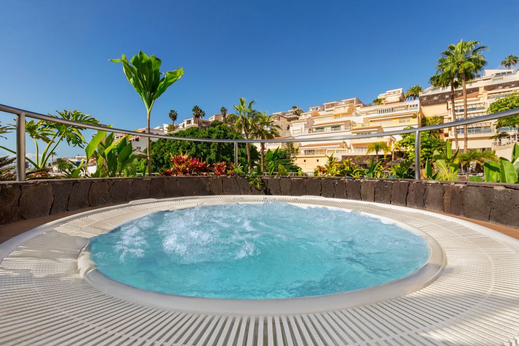 Jacuzzi omringd door planten met gebouwen op de achtergrond op Tenerife.