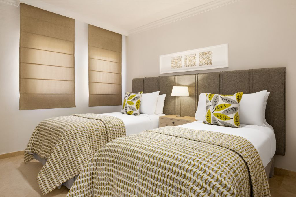 Twee eenpersoonsbedden met patroonbedekte bedden en kussens in een hotelkamer op Tenerife.
