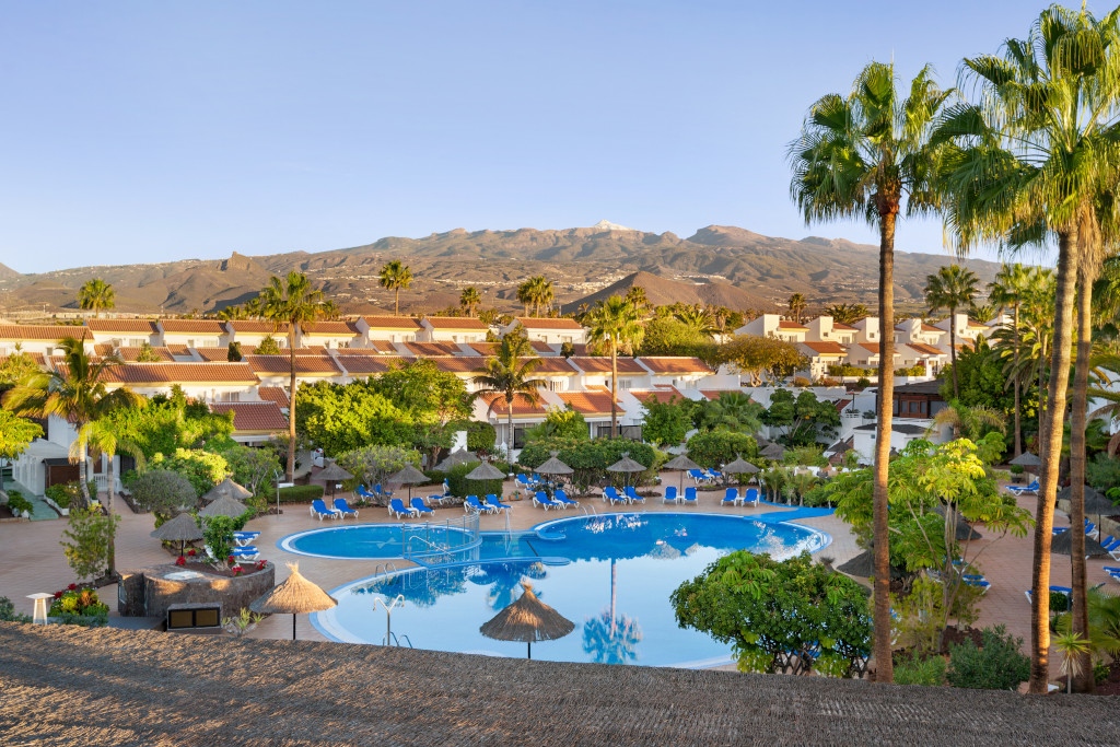 Toeristisch complex op Tenerife met een zwembad en bergen op de achtergrond.