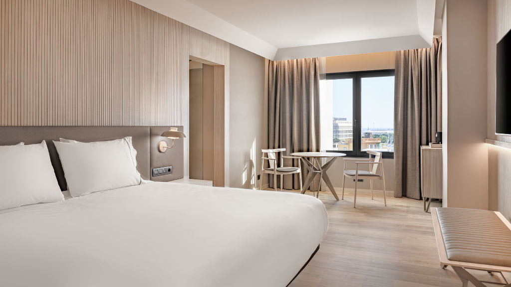 Hotelkamer op Tenerife met een tweepersoonsbed, tafel en stoelen bij het raam.