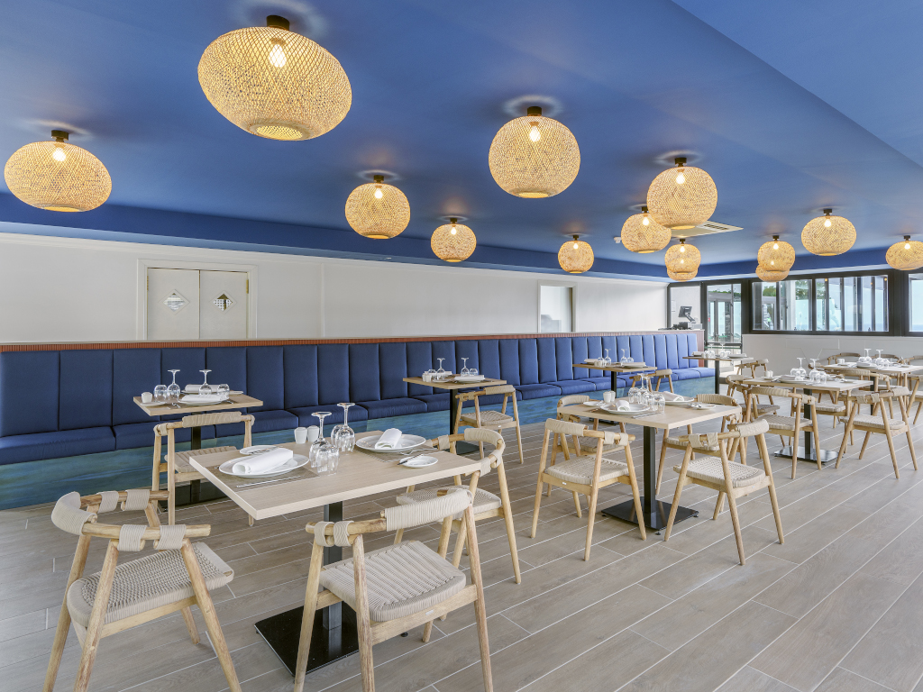 Restaurant met houten tafels en stoelen, moderne verlichting en blauwe decoratie op Tenerife.