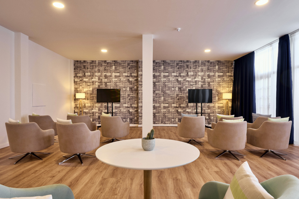 Vergaderruimte op Tenerife met beige stoelen en twee tv-schermen.
