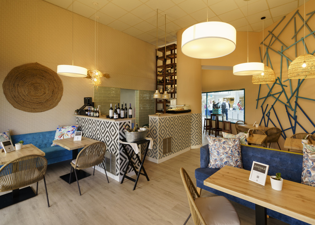 Interieur van een café op Tenerife met houten tafels, rotan stoelen en flessen wijn.