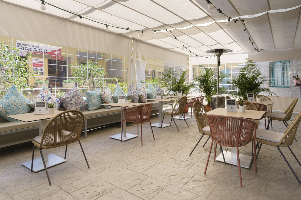 Caféterras op Tenerife met kleurrijke tafels, stoelen en kussens.