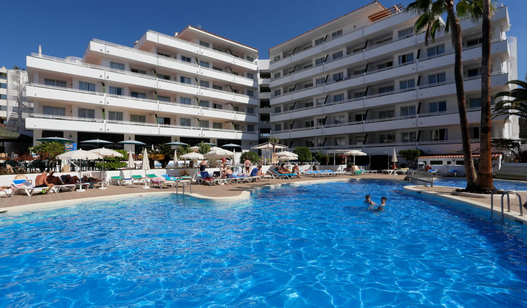 Zwembad met ligbedden en appartementencomplex op Tenerife.