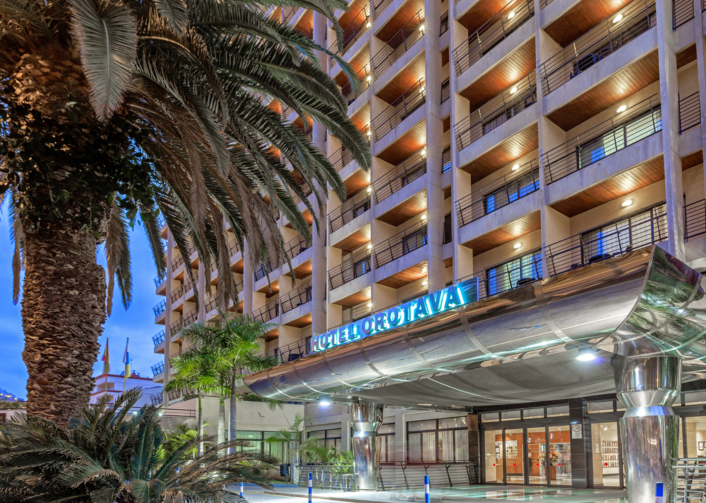 Verlichte ingang van Hotel Orotava op Tenerife, omringd door palmbomen.