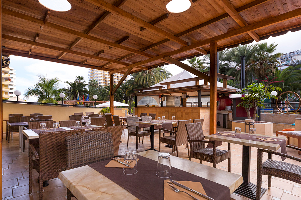Terras met rieten tafels en stoelen onder een pergola in een restaurant op Tenerife.
