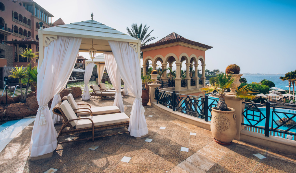 Terras met ligstoelen en pergola gericht op het zwembad en de zee op Tenerife.