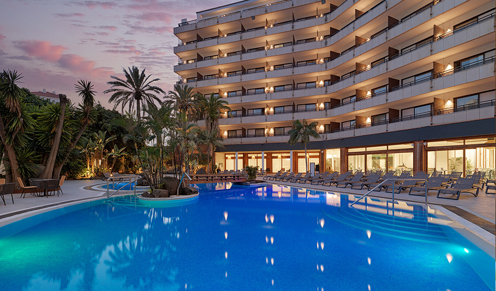 Zwembad bij zonsondergang voor een hotel op Tenerife met palmbomen.