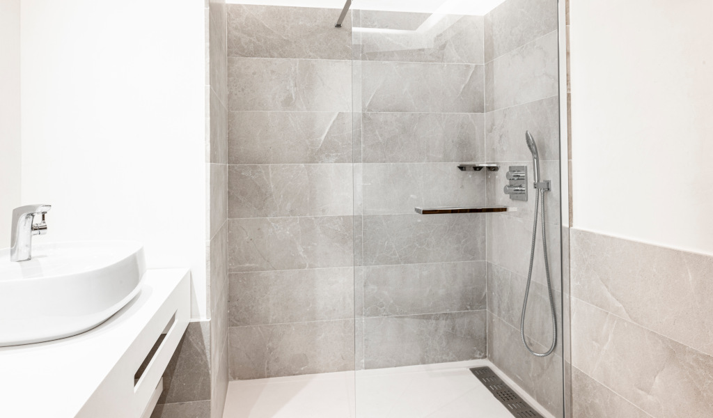 Grijze betegelde douche en keramische wastafel in een hotel op Tenerife.