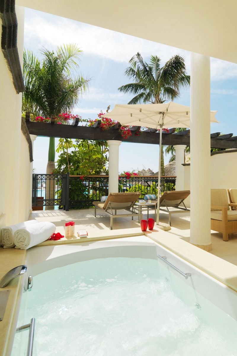 Terras met jacuzzi, ligstoelen en parasol in een hotel op Tenerife.