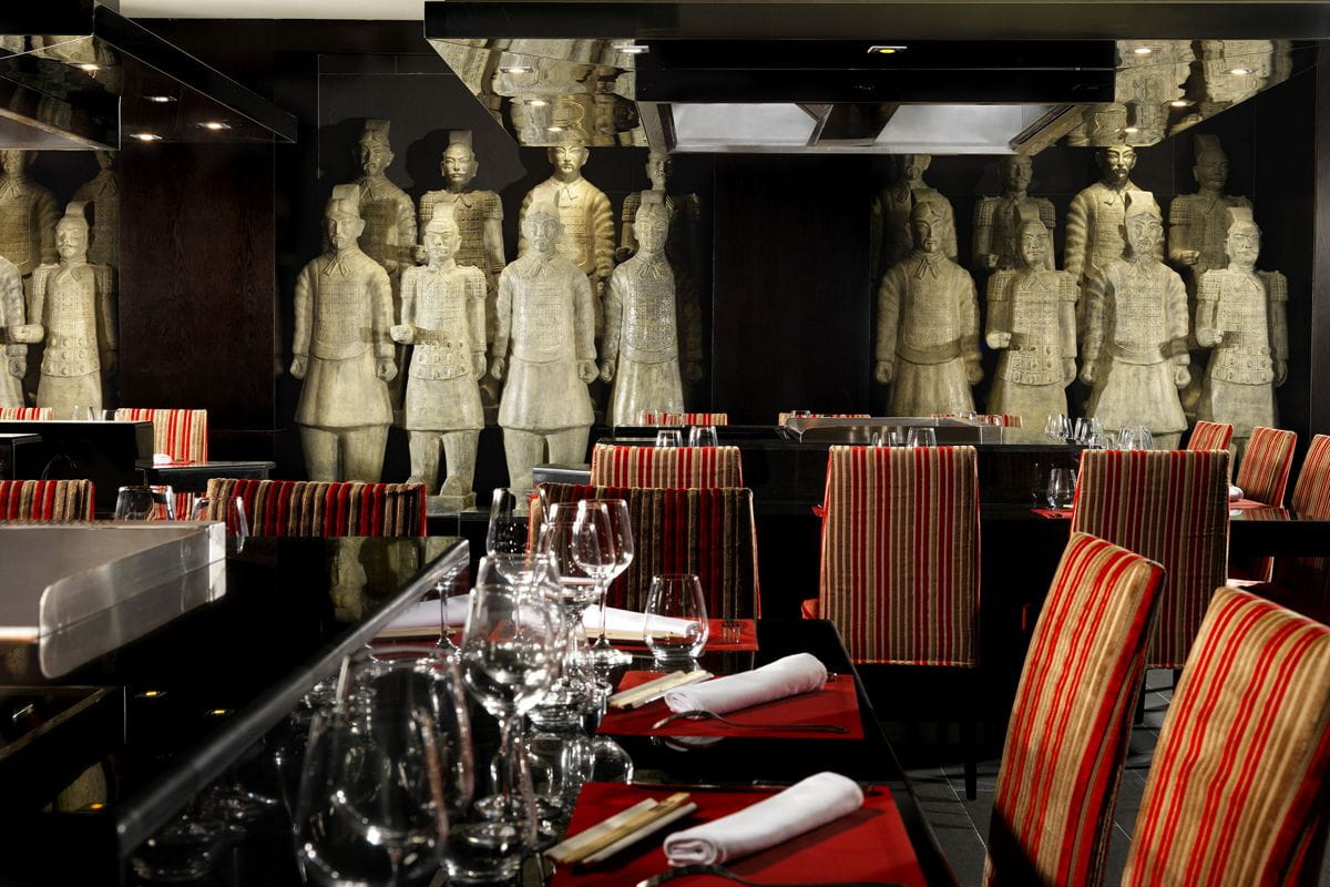 Restaurant op Tenerife met terracotta warrior-decoratie en voorbereide tafels.