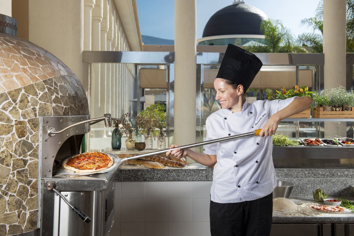 Chef die pizza bereidt in een stenen oven in een restaurant op Tenerife.