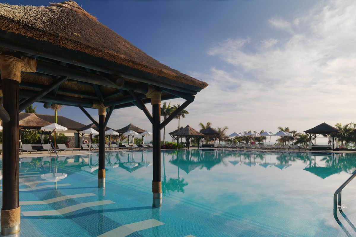 Buitenzwembad met palapas en ligstoelen in een resort op Tenerife.