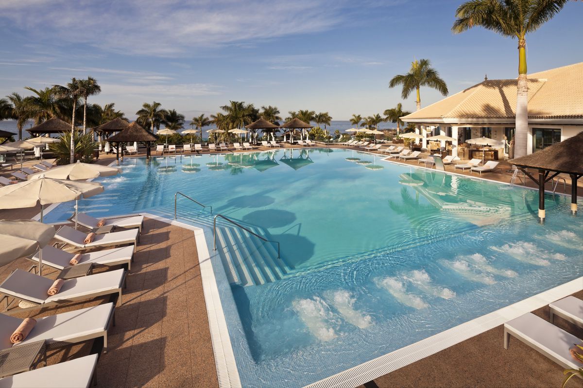 Zwembad met ligstoelen en parasols in een resort op Tenerife.
