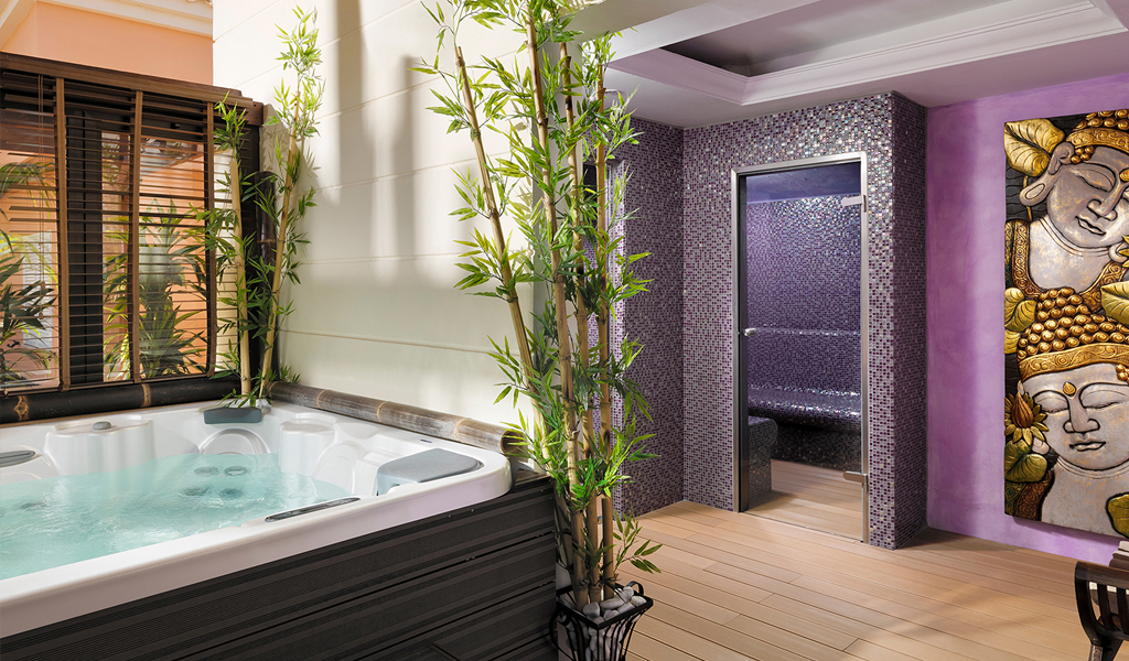Jacuzzi en stoombad in een spa op Tenerife, versierd met bamboe en kunst aan één muur.