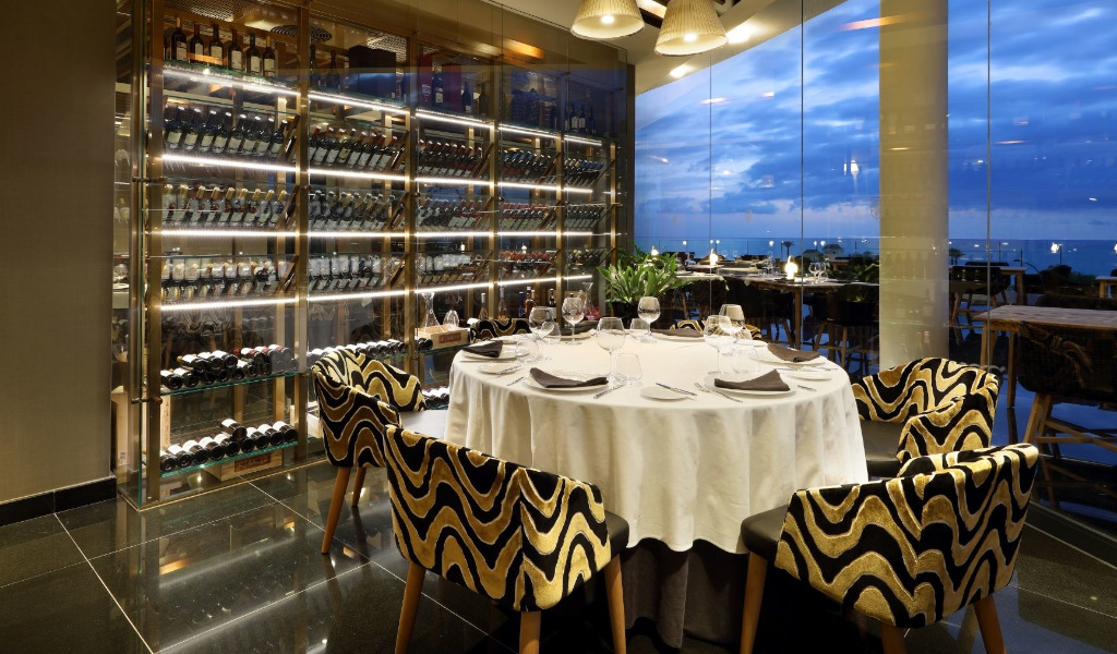 Ronde tafel met glazen in een elegant restaurant op Tenerife, naast een wijnrek.