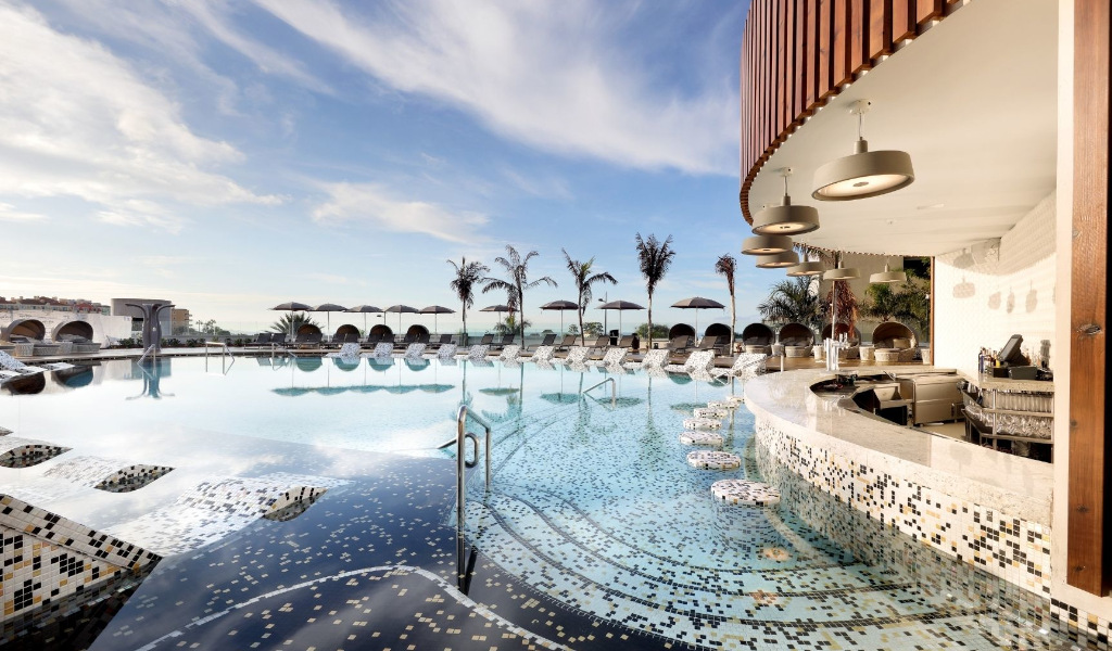 Infinity pool met bar en ligstoelen op Tenerife onder een blauwe lucht.