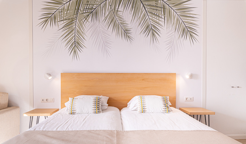 Dubbelbed met houten hoofdeinde en bladdruk aan de muur in Tenerife.