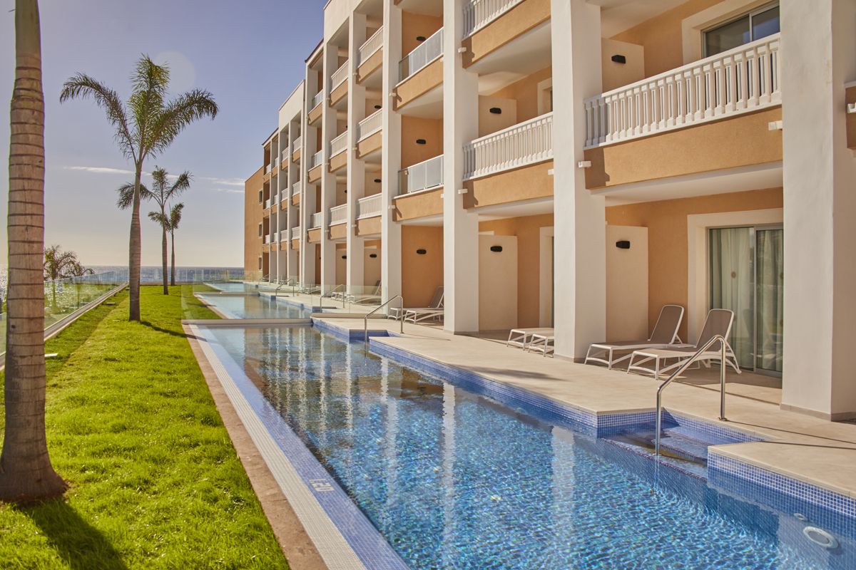 Hotel met zwembad en palmbomen op Tenerife met uitzicht op de oceaan.