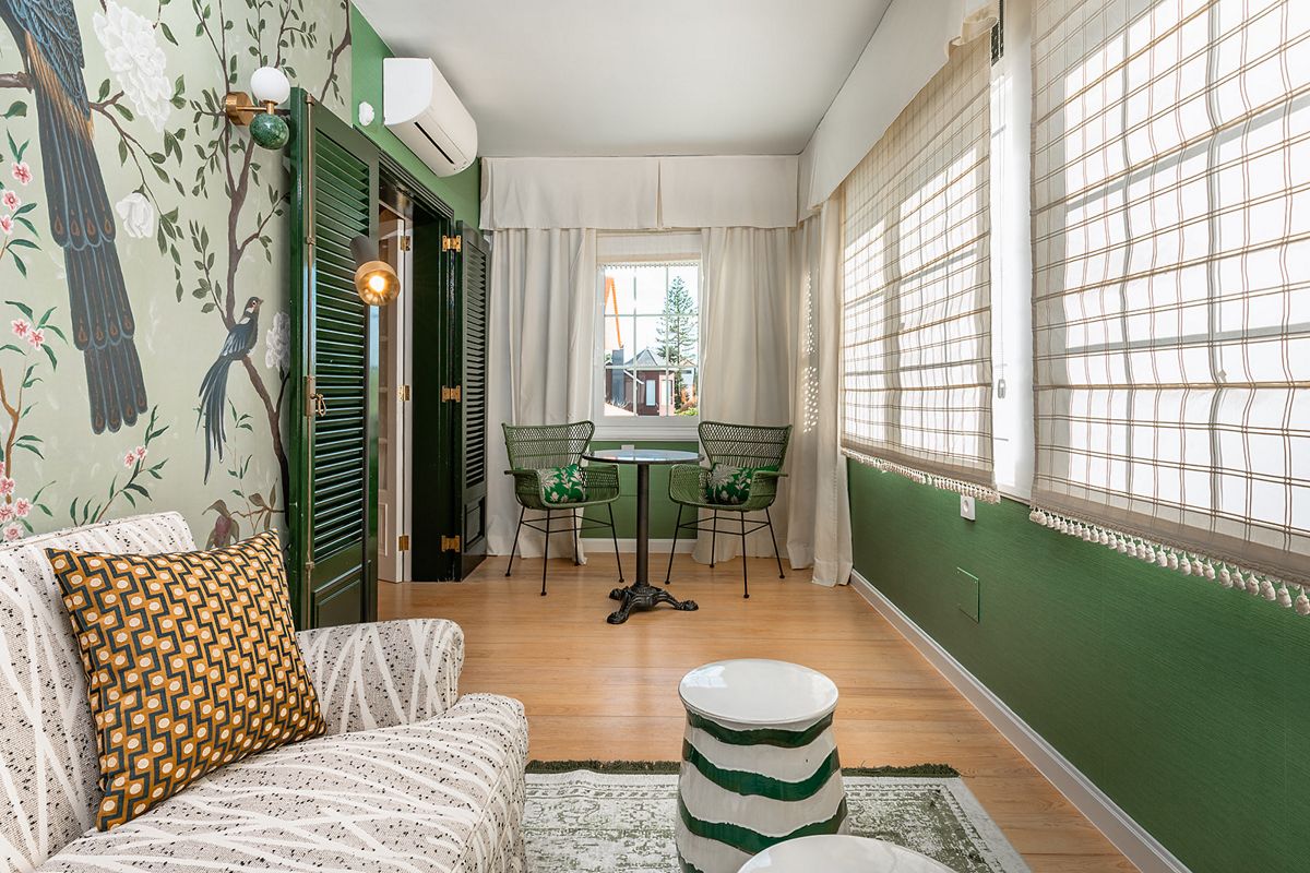 Woonkamer op Tenerife met een bank, ronde tafel en groene stoelen naast het raam.