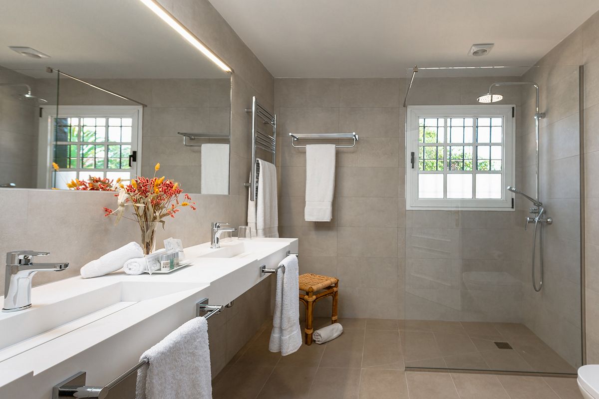 Moderne badkamer met douche en wastafel op Tenerife, handdoeken en een groot raam.