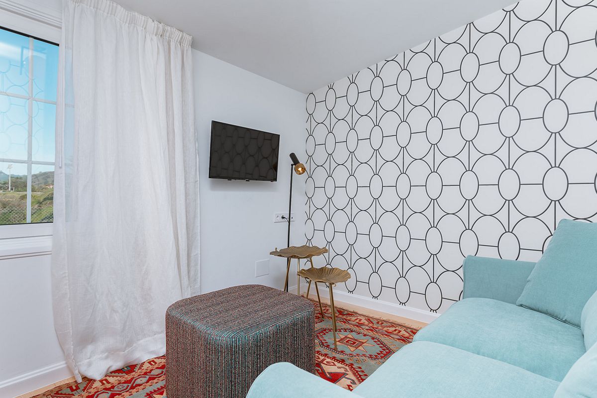 Woonkamer met blauwe bank, decoratief tapijt en tv in een huis op Tenerife.