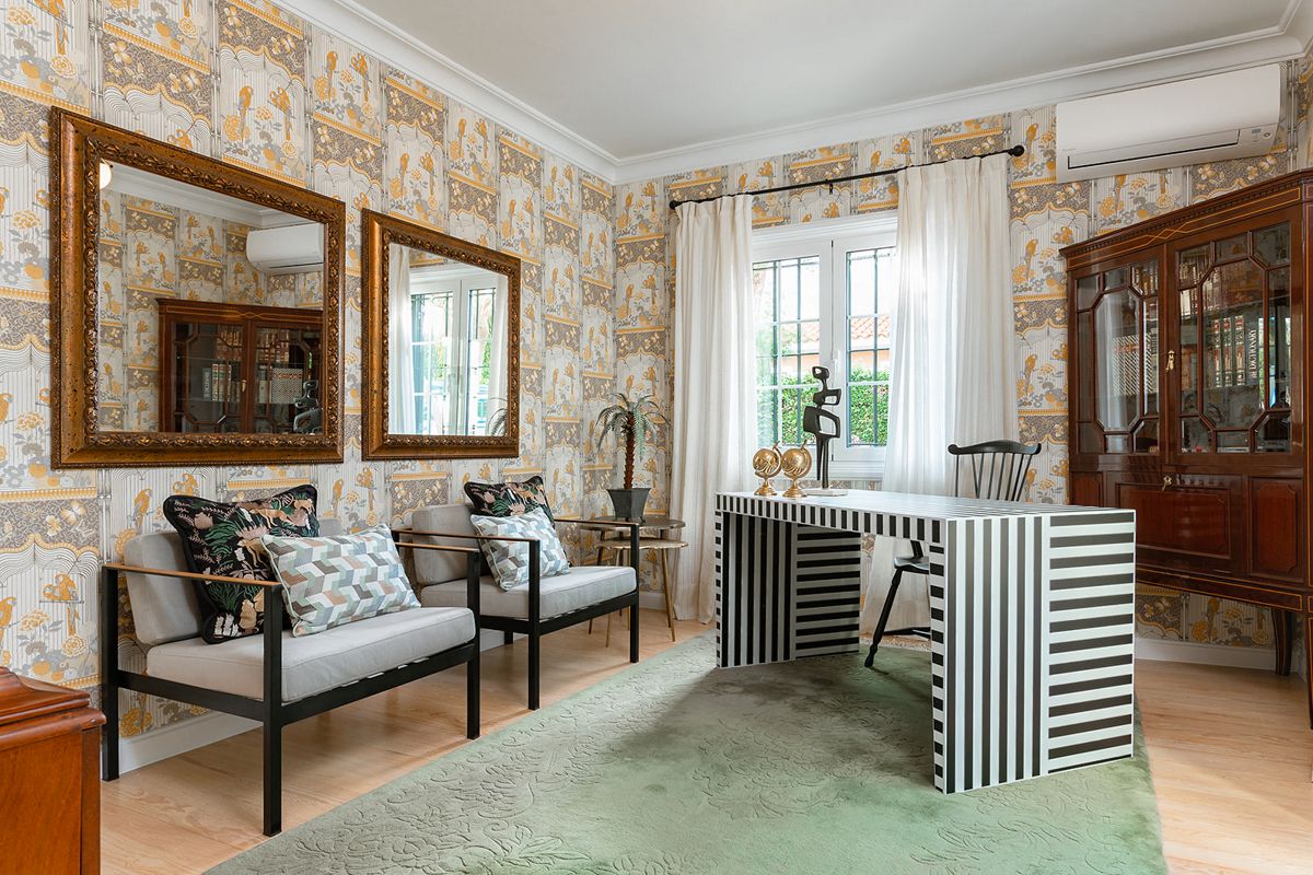 Woonkamer met gestreept bureau, grijze stoelen en decoratief behang in Tenerife.