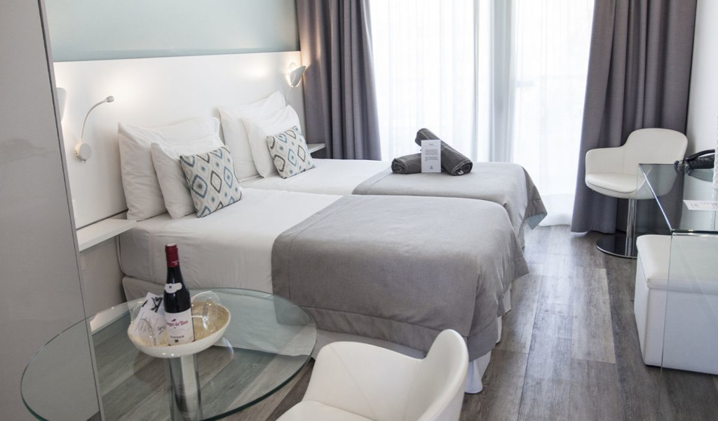 Hotelkamer op Tenerife met twee eenpersoonsbedden en flessen wijn op tafel.