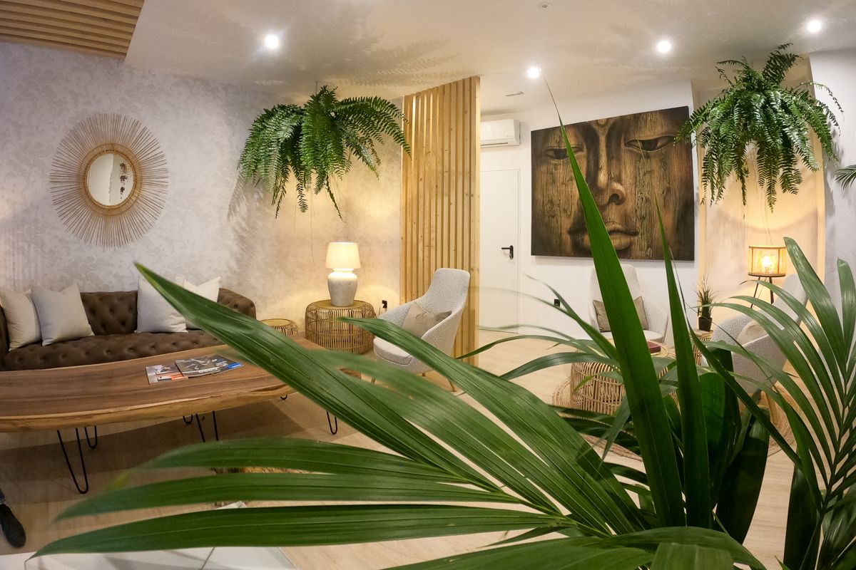 Wachtkamer versierd met planten, een bruine bank en een ronde spiegel op Tenerife.