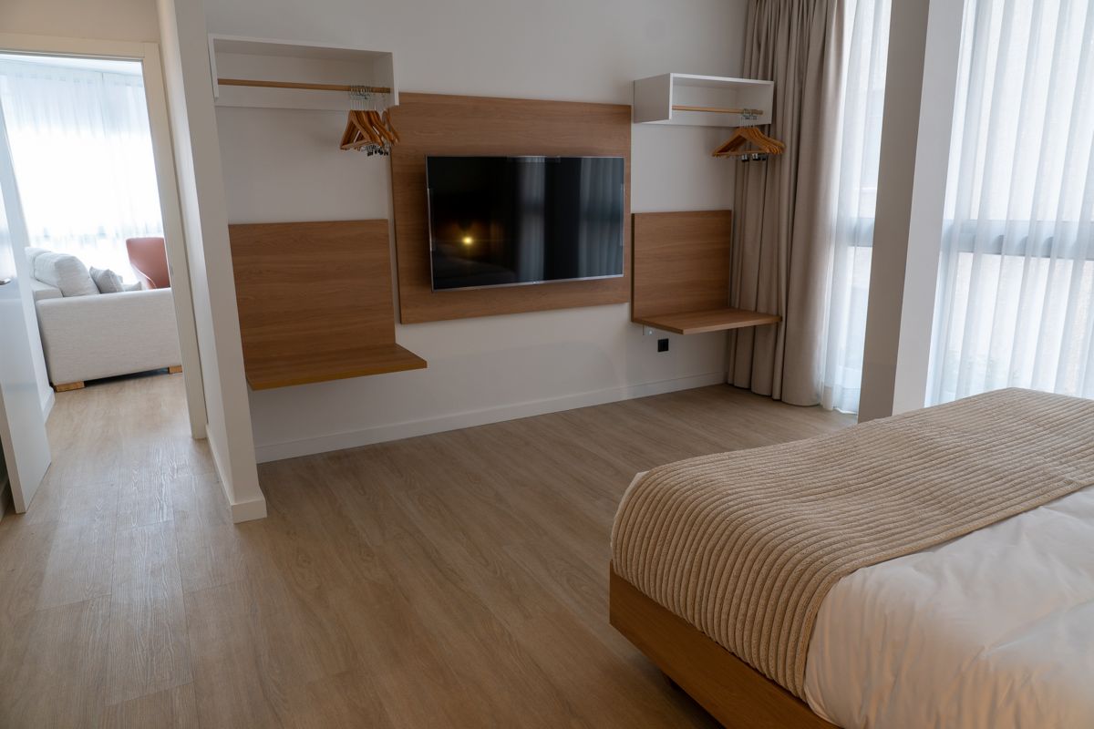 Kamer met bed, tv, planken en een groot raam in een hotel op Tenerife.
