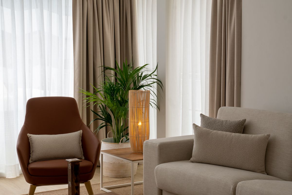 Woonkamer met fauteuil, bank, brandende lamp en plant op Tenerife.