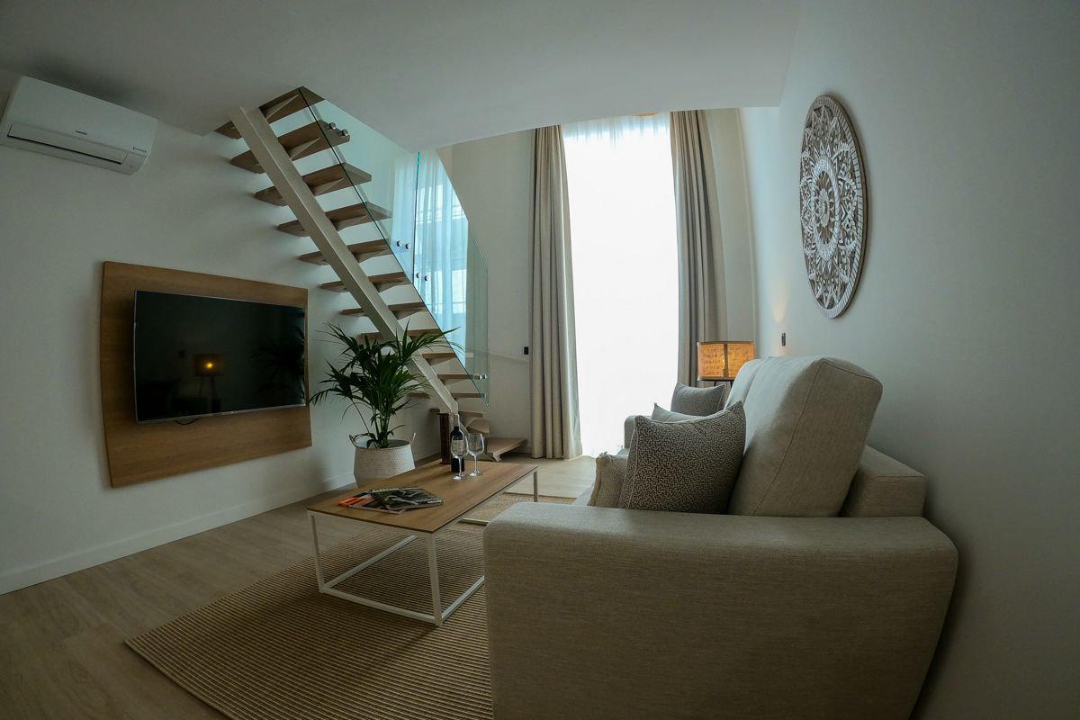 Moderne woonkamer op Tenerife met bank, ladder en tv aan de muur.