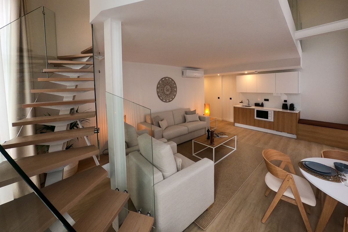 Moderne kamer met houten trap en geïntegreerde keuken in een appartement op Tenerife.