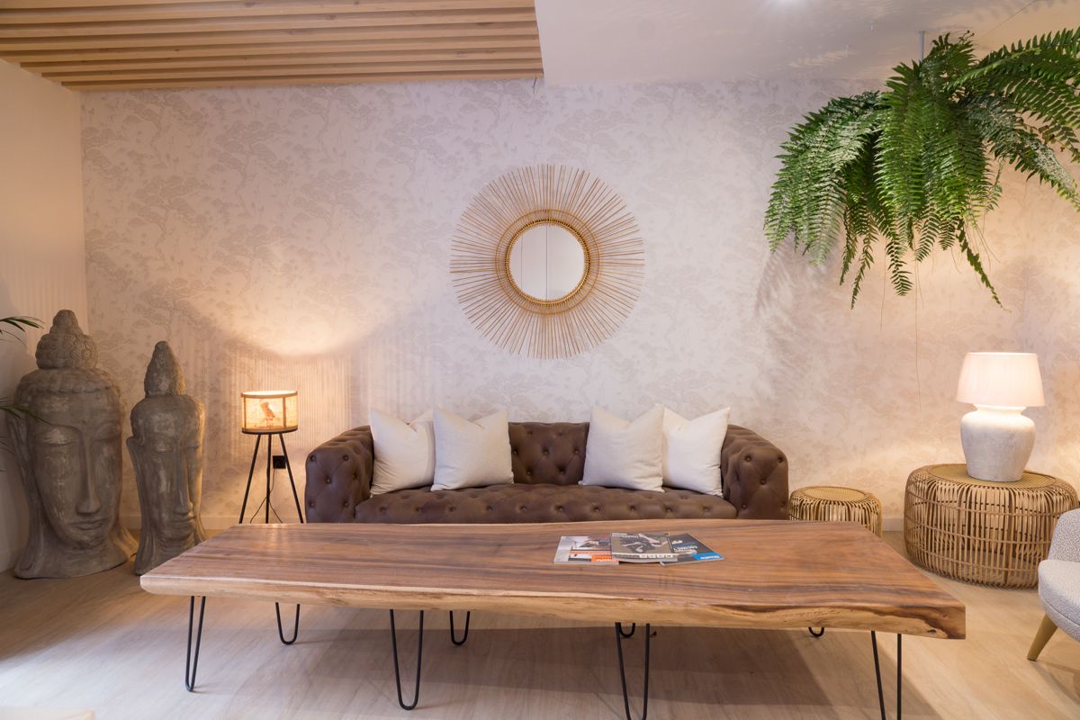 Woonkamer op Tenerife met bank, houten tafel, Boeddhafiguren en hangende plant.