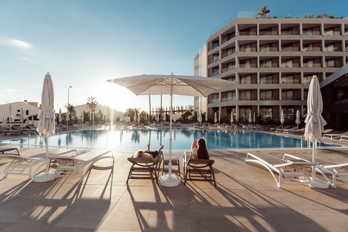 Hotelzwembad op Tenerife met ligstoelen en parasols bij zonsondergang.