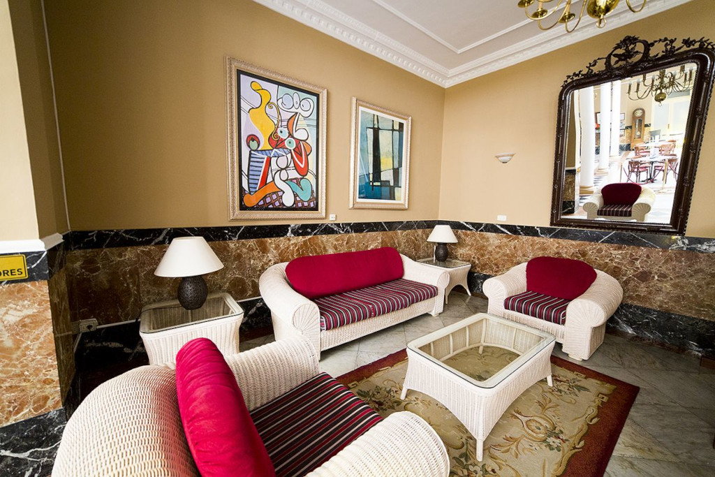 Woonkamer met rode banken en tafels naast een grote spiegel in een hotel op Tenerife.