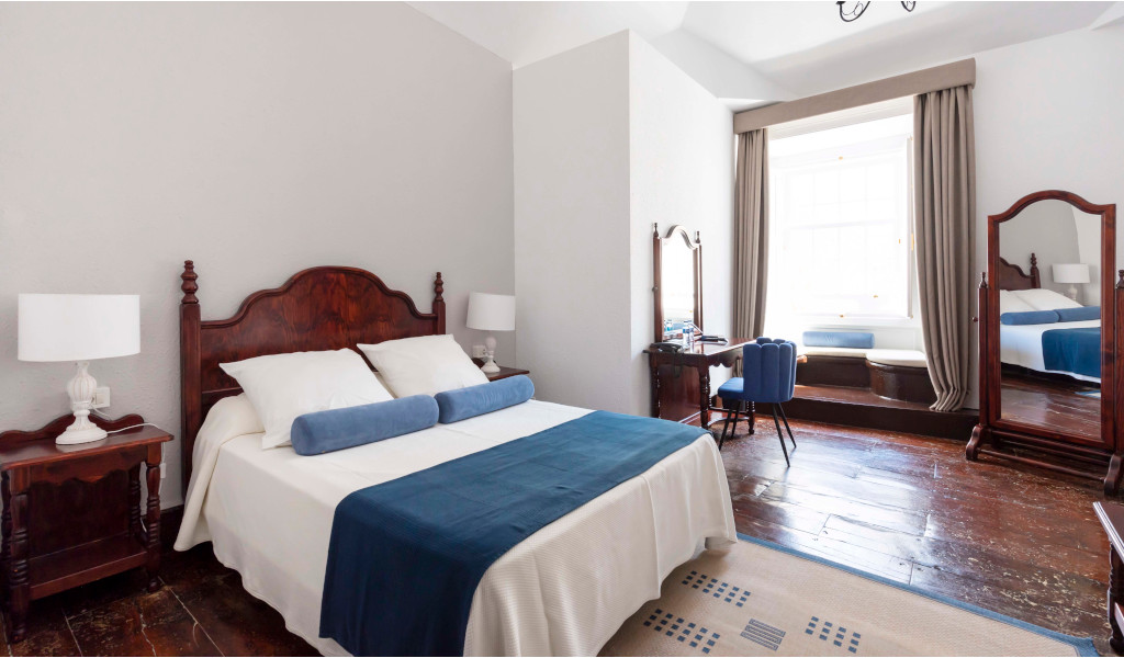 Slaapkamer met tweepersoonsbed, twee lampen, spiegel en raam. Locatie: Tenerife.