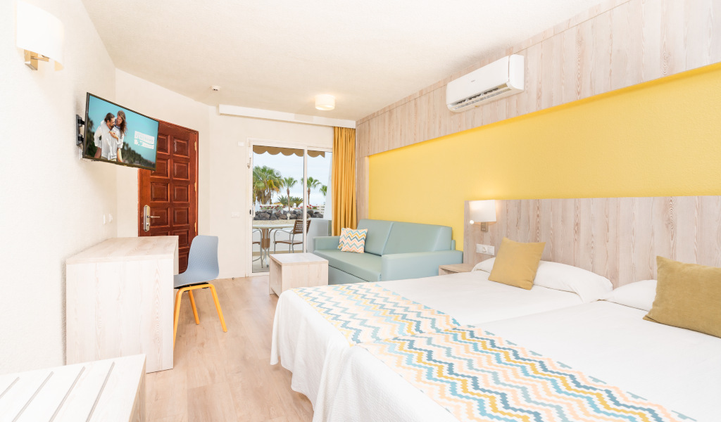 Hotelkamer op Tenerife met tweepersoonsbed, bank en televisie.