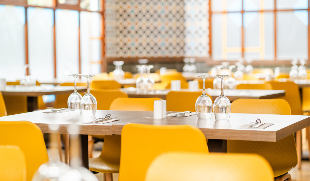Tafels in een restaurant met drankjes en gele stoelen op Tenerife.