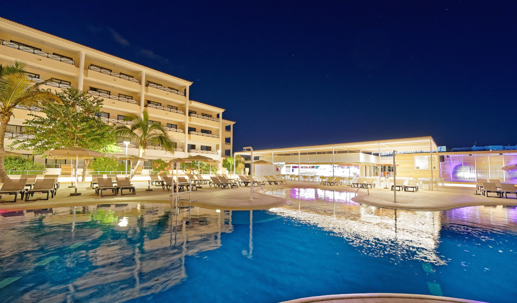 Verlicht zwembad voor een vier verdiepingen tellend hotel op Tenerife, sterrennacht.