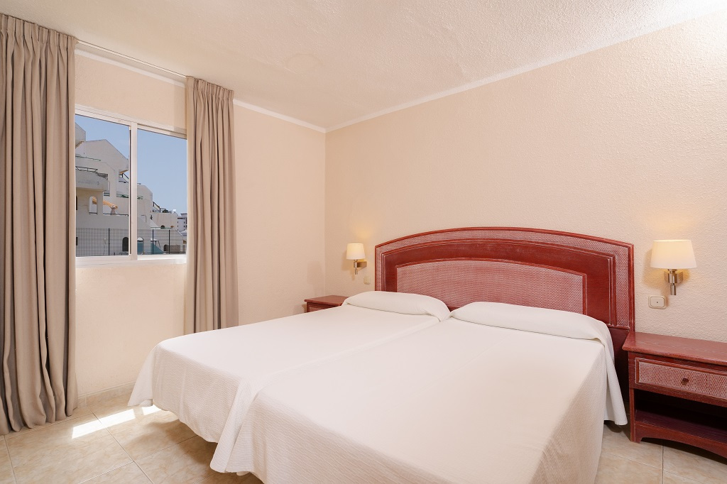 Twee eenpersoonsbedden in een kamer met raam en lamp op Tenerife.
