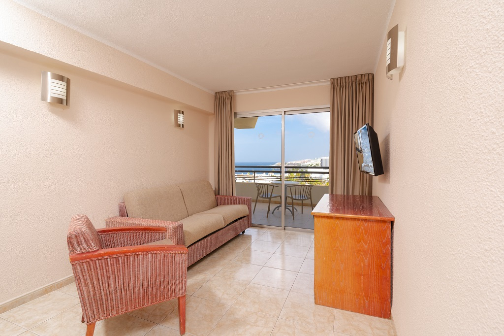 Woonkamer met bank, televisie en balkon met zeezicht op Tenerife.