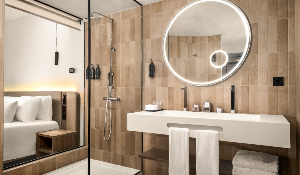 Moderne badkamer met ronde spiegel, douche en gedeeltelijk kamerzicht op Tenerife.