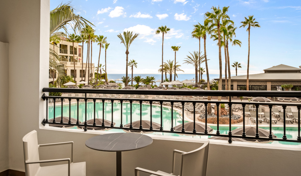 Terras met uitzicht op het zwembad en de palmbomen in een hotel op Tenerife.
