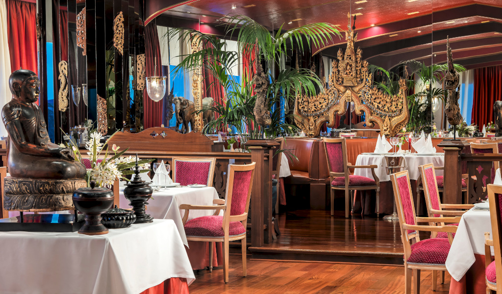 Restaurant versierd met sculpturen en planten op Tenerife, tafels met rode stoelen.