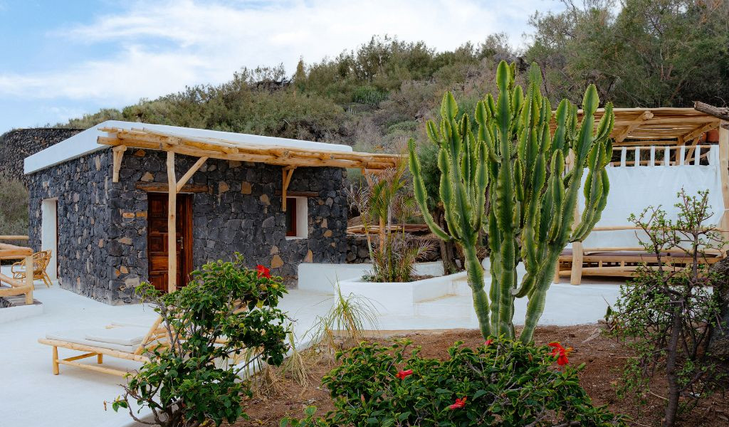 Stenen en cactus landhuis op Tenerife, omringd door groen en houten meubels.