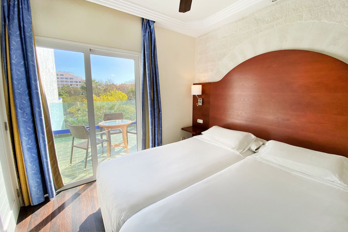 Kamer met twee bedden, uitzicht op het balkon met stoelen en tafel op Tenerife.