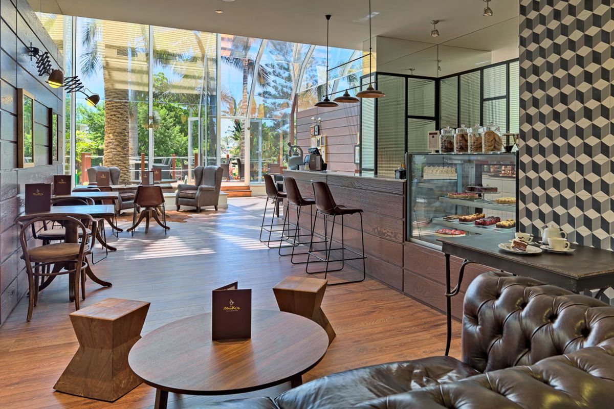 Modern café op Tenerife met houten meubels, taartenvitrines en grote ramen.